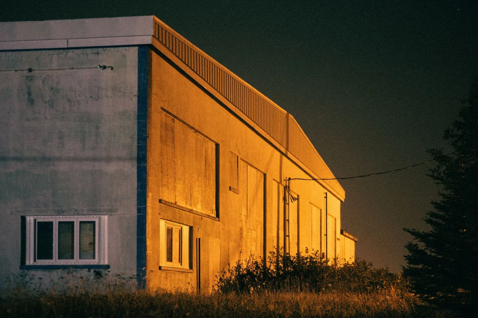 Bâtiment industriel éclairé à la tombée de la nuit.